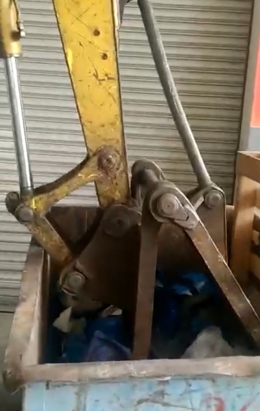 An excavator crushing scrap in a steel bin