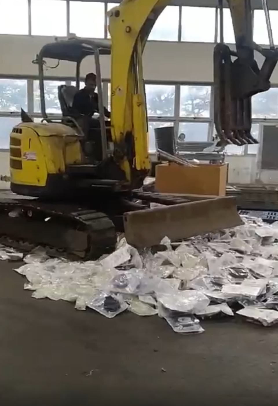 An excavator crushing bagged scrap on the yard floor